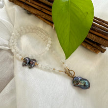 Lade das Bild in den Galerie-Viewer, White moonstone bead necklace with 6mm beads, featuring a side black peacock pearl and a baroque pearl pendant, accented with a gold bronze artisan toggle and gold-filled details. This 18-inch necklace is an elegant June birthstone gift for her.
