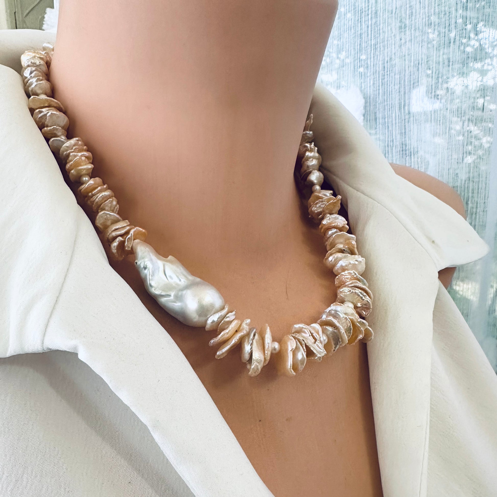 Side close-up of peach keshi pearl necklace on mannequin highlighting natural petal pearls