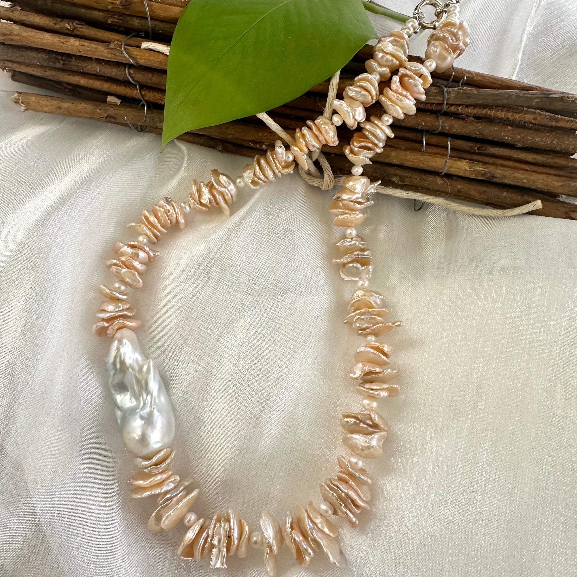 Front view of peach keshi pearl necklace on mannequin showing white baroque pearl detail