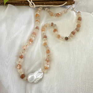 Hand-knotted necklace with mixed moonstone and a baroque pearl at the center, threaded with orange string, 20 inches long, featuring a sterling silver marine clasp.