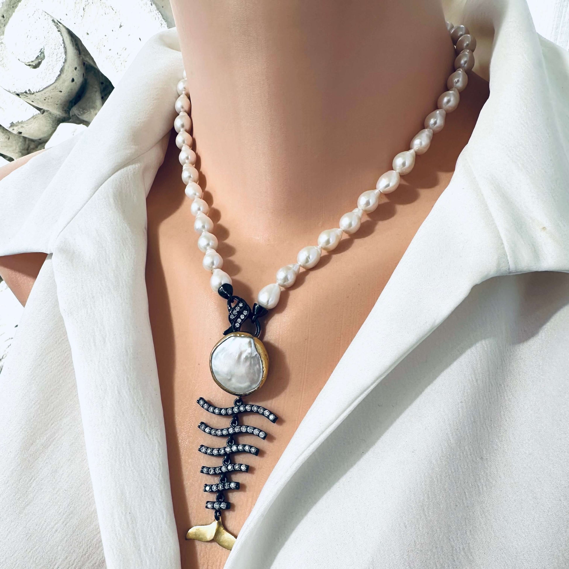 Close up small baroque pearl necklace fishbone pendant on white blouse handmade in Canada
