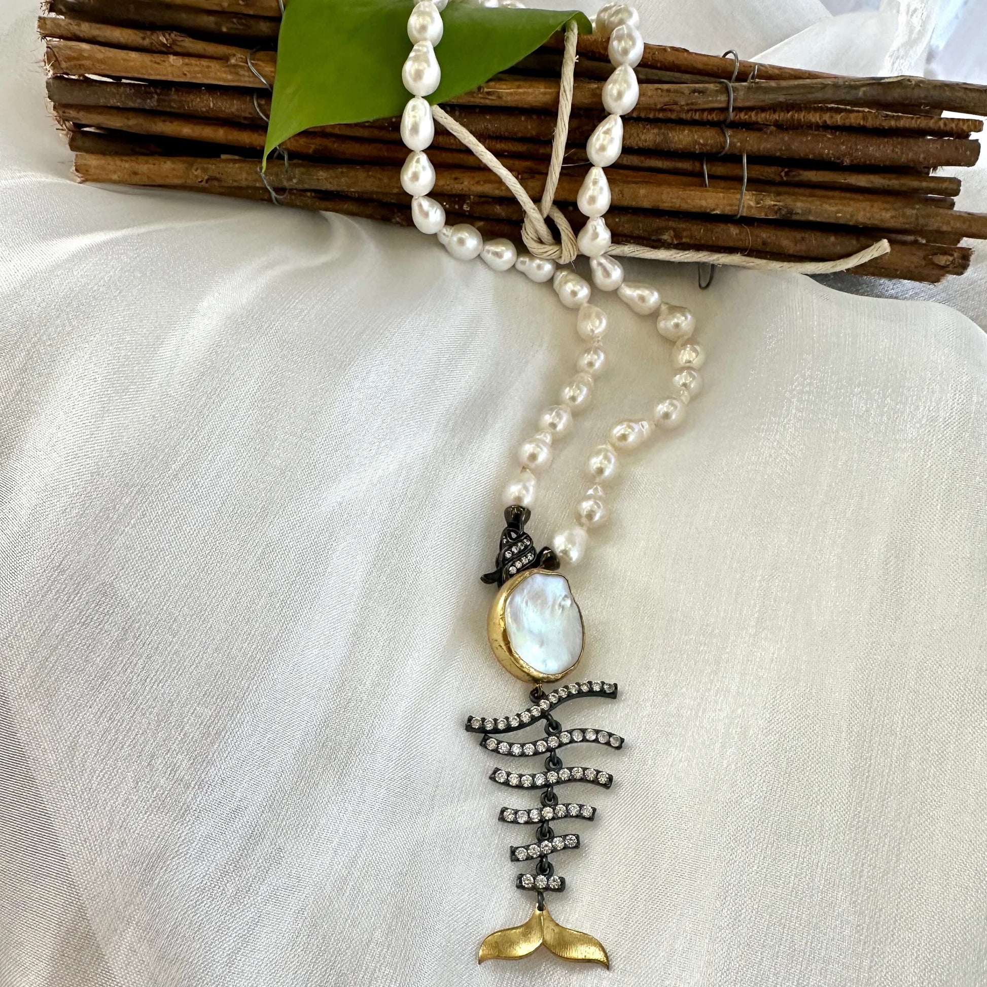 Close up small baroque pearl necklace fishbone pendant on white blouse handmade in Canada