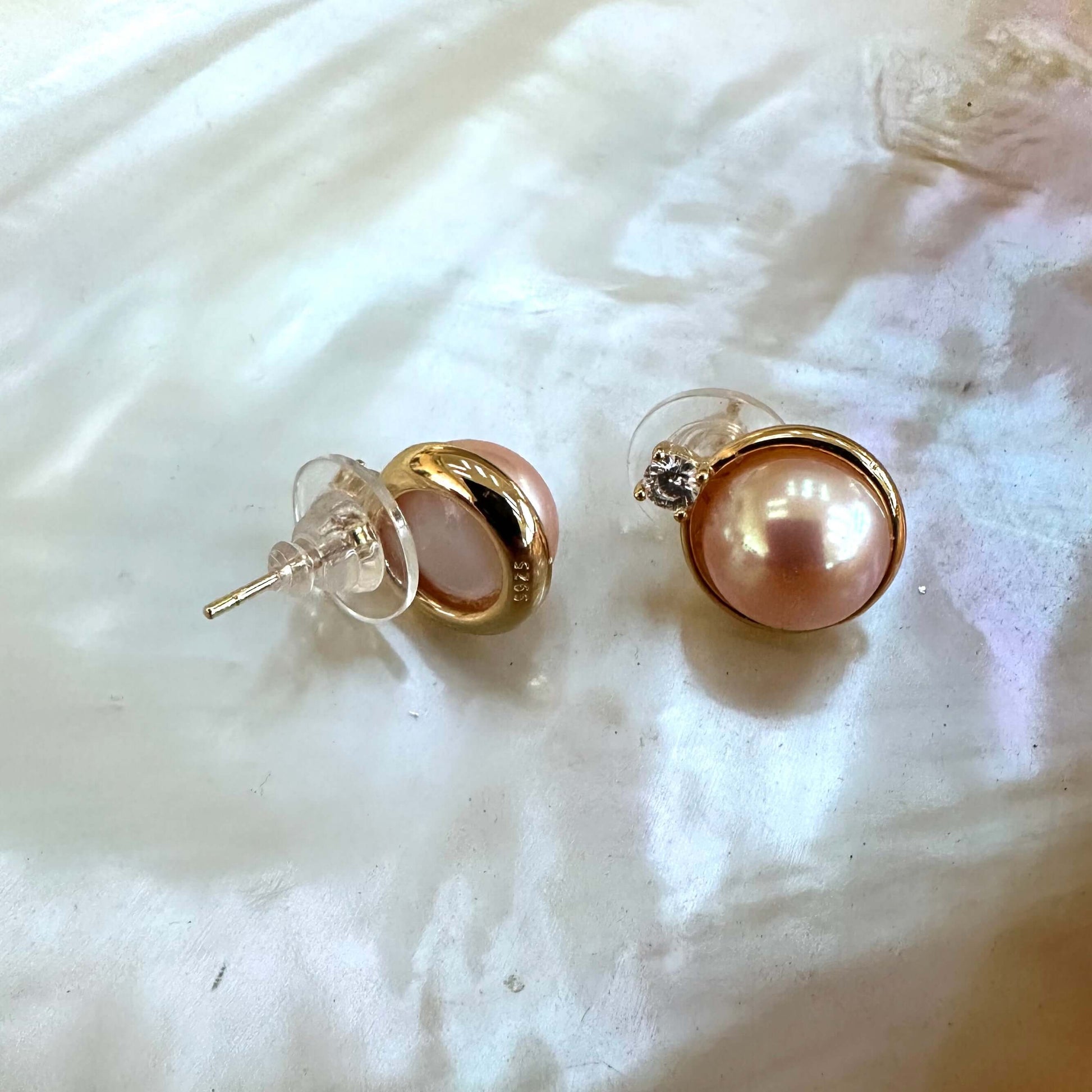 Front and back view of Edison Mabe pearl stud earrings on white pearl shell handmade in Canada