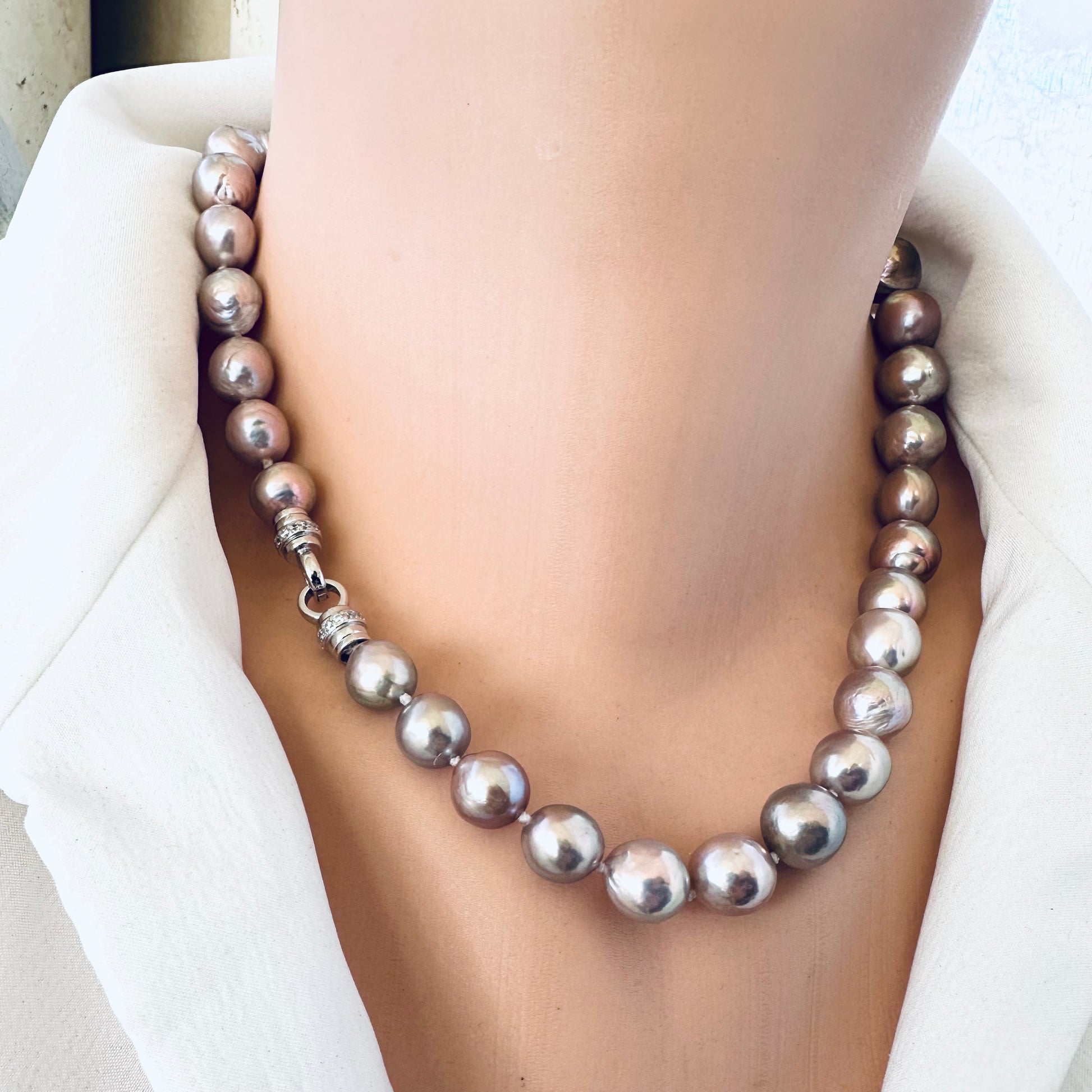 Elegant pink lavender pearl necklace displayed on mannequin, highlighting iridescent hues of pink, purple, and soft green.