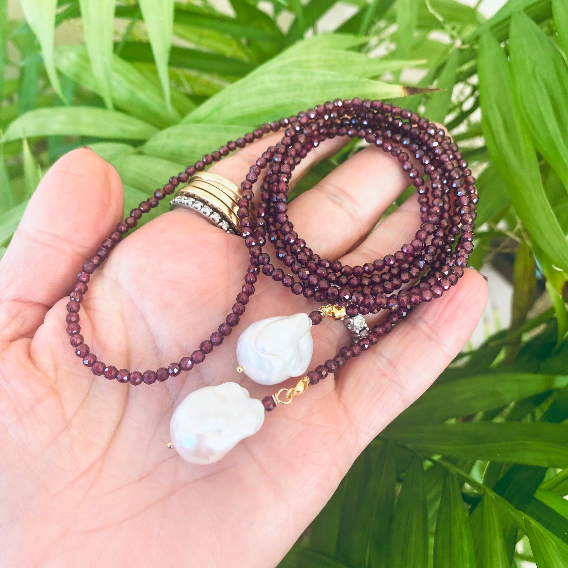 Red Garnet Lariat Necklace close-up in hand with faceted garnet beads and baroque pearls