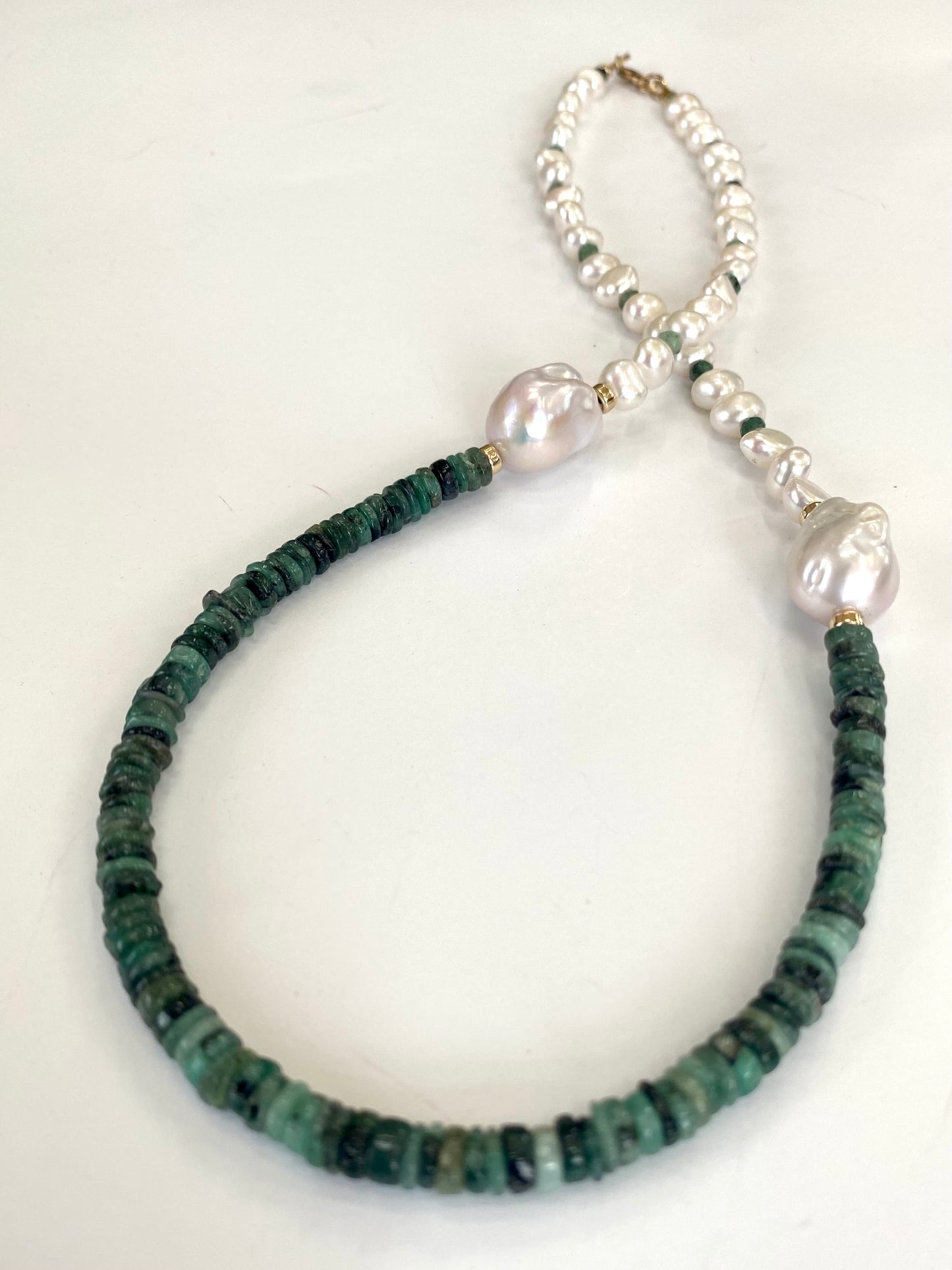 Emerald baroque pearl necklace featuring asymmetric design with emerald disk beads and baroque pearls.
