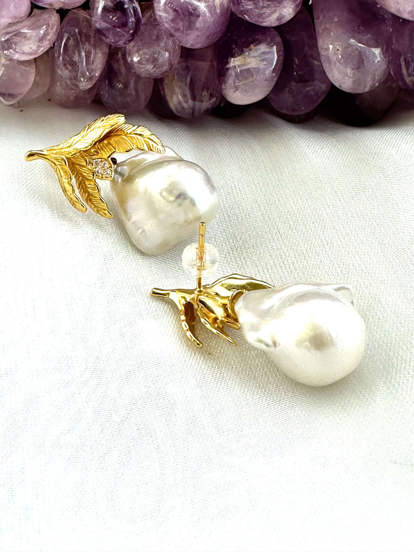 Baroque Pearl Earrings with gold vermeil oak leaf accents displayed beside raw amethyst gemstone on white backdrop.
