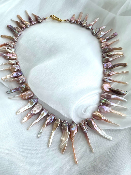 Close-up of pink Biwa pearl necklace showing purplish-pink luster on fabric