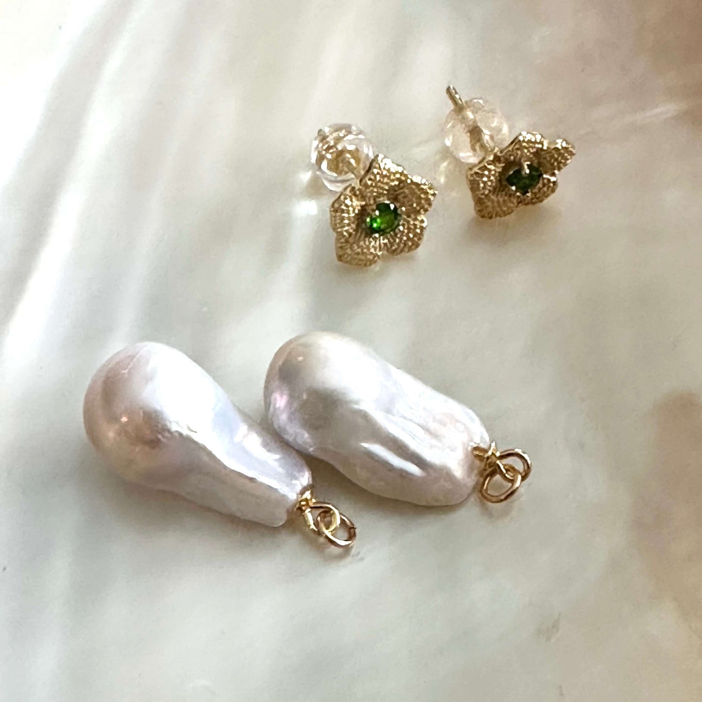 Convertible chrome diopside pearl earrings with separate stud and pearl drop pieces on shell background