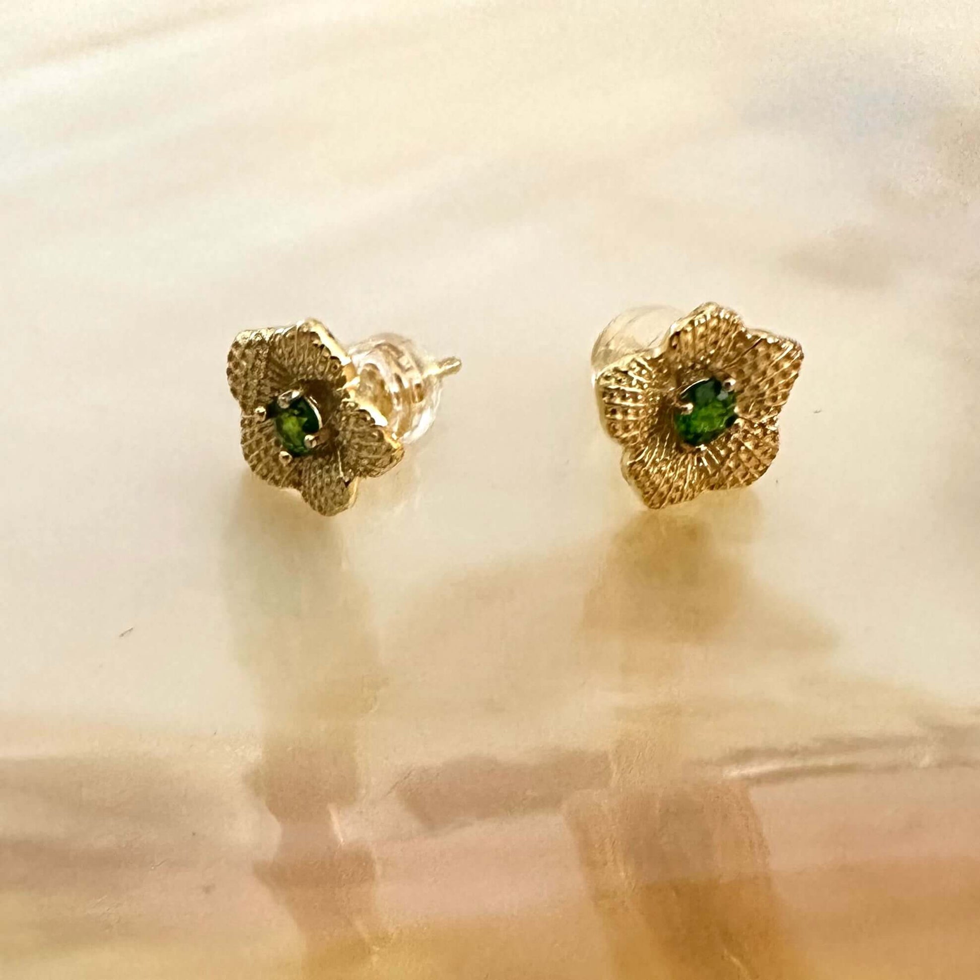 Chrome diopside flower stud earrings in gold vermeil displayed on pearl background