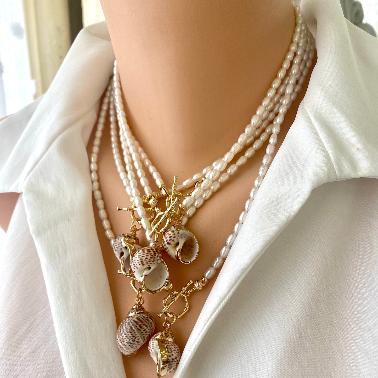 Real seashell pendant pearl necklace layered with gold chains for a beach-inspired look