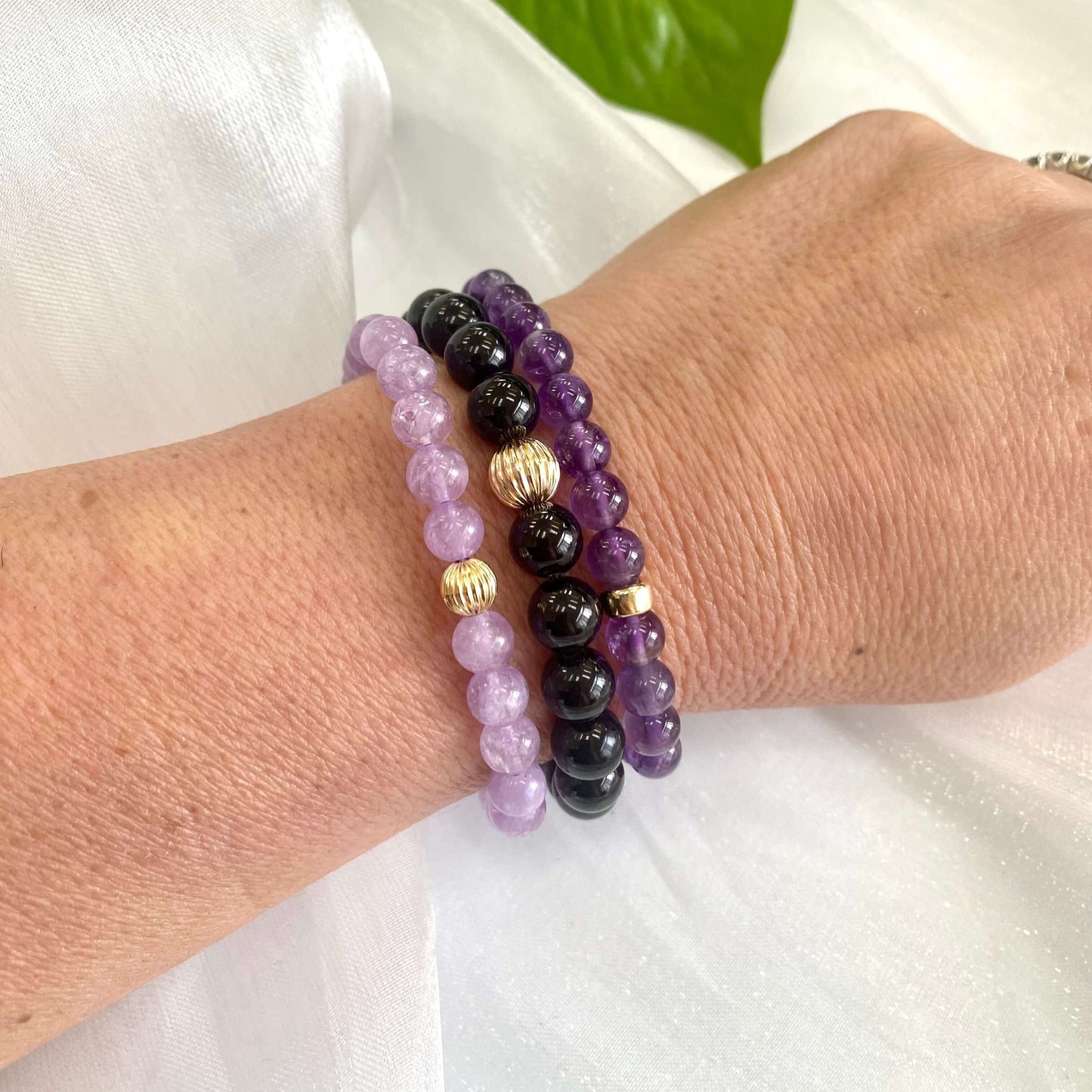 Lavender amethyst stretch bracelet featuring 6mm and 8mm beads stacked on a wrist with gold accents.