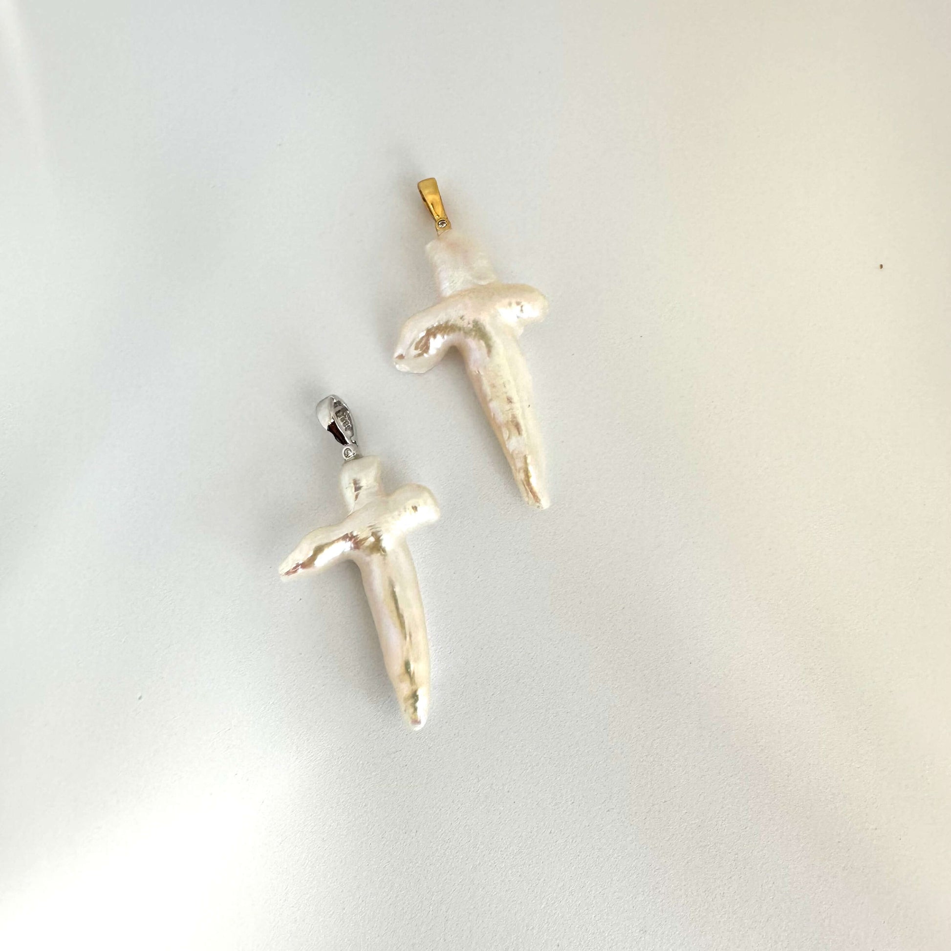 Baroque pearl cross pendant close-up on white background, luminous handcrafted detail.