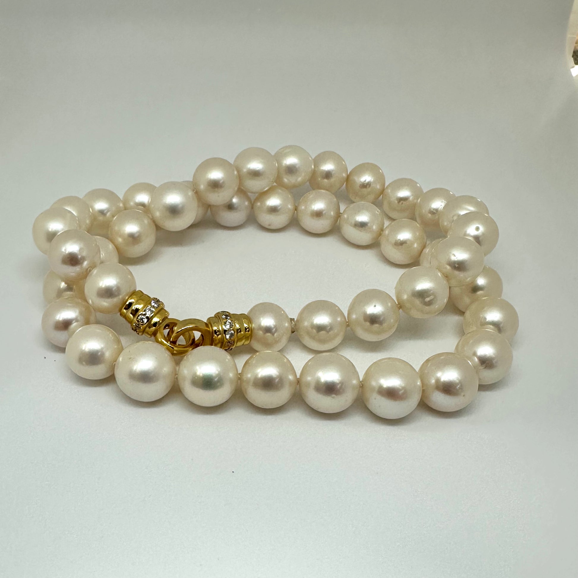 Close-up of white pearl necklace cross pendant against white background — near-round freshwater pearls with natural luster