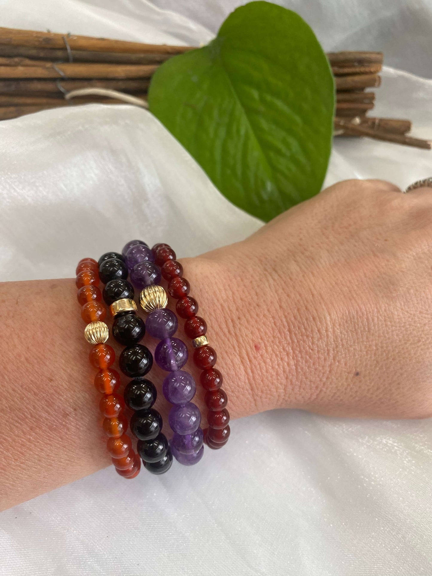 Red agate bracelet with 6mm beads and 14K gold filled accents, stacked with other bracelets on a wrist.