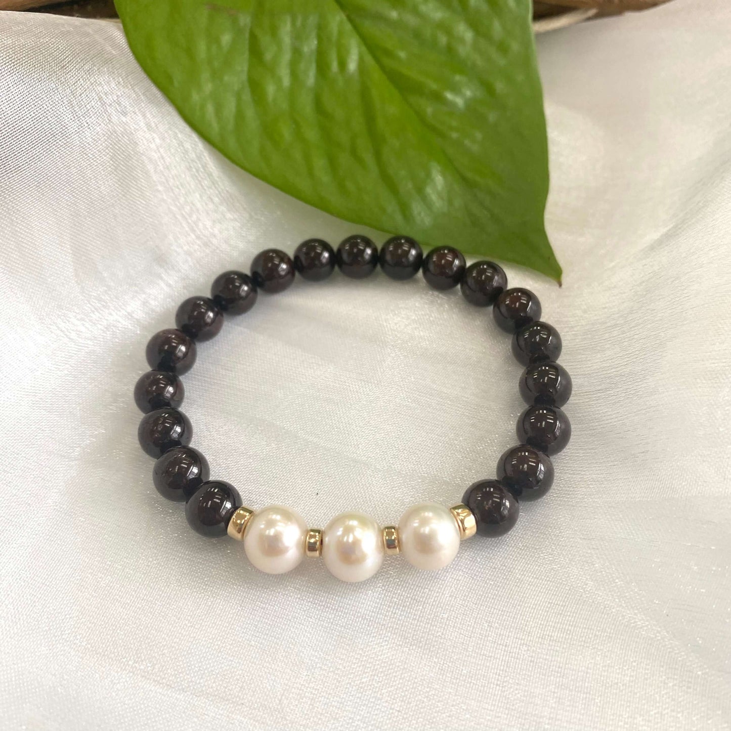 Dark Red Garnet Bracelet with three pearls displayed on white cloth – detailed shot