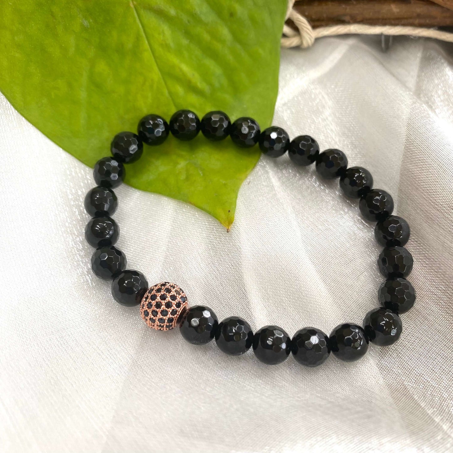 Black Onyx mens bracelet showcasing round black onyx beads with a rose gold spacer on a natural background.