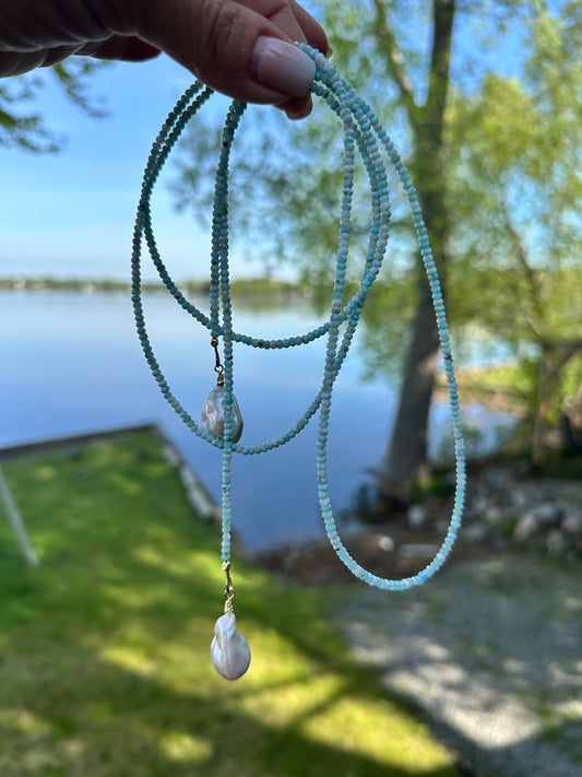 Blue Larimar Lariat Necklace held against lake and grass background — natural gemstone and pearl necklace handcrafted by Loulia Pearl Jewelry