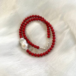 red coral and one large baroque pearl on the side of the necklace with sterling silver details, measuring 18 inches. This vibrant jewelry piece makes a thoughtful gift for her.
