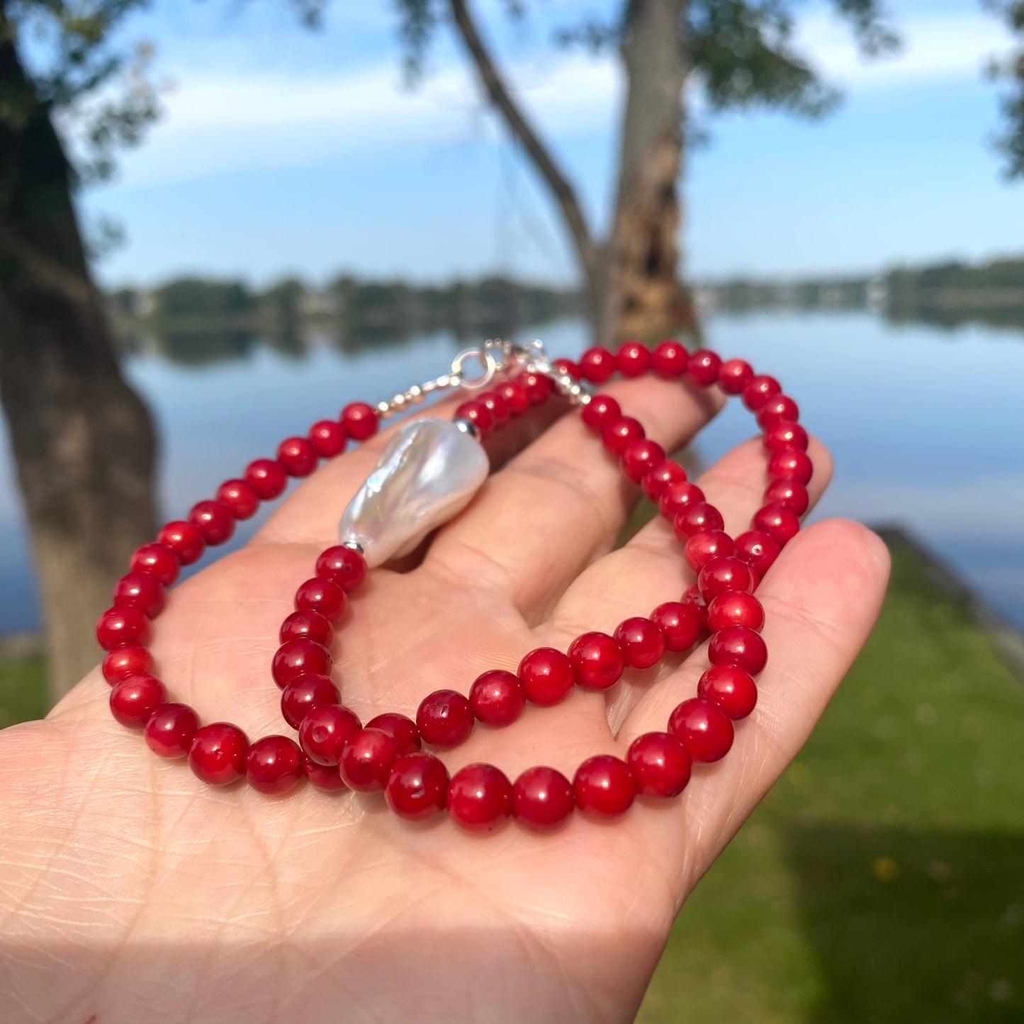 red coral and one large baroque pearl on the side of the necklace with sterling silver details, measuring 18 inches. This vibrant jewelry piece makes a thoughtful gift for her.