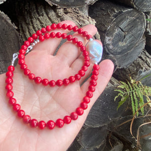 red coral and one large baroque pearl on the side of the necklace with sterling silver details, measuring 18 inches. This vibrant jewelry piece makes a thoughtful gift for her.