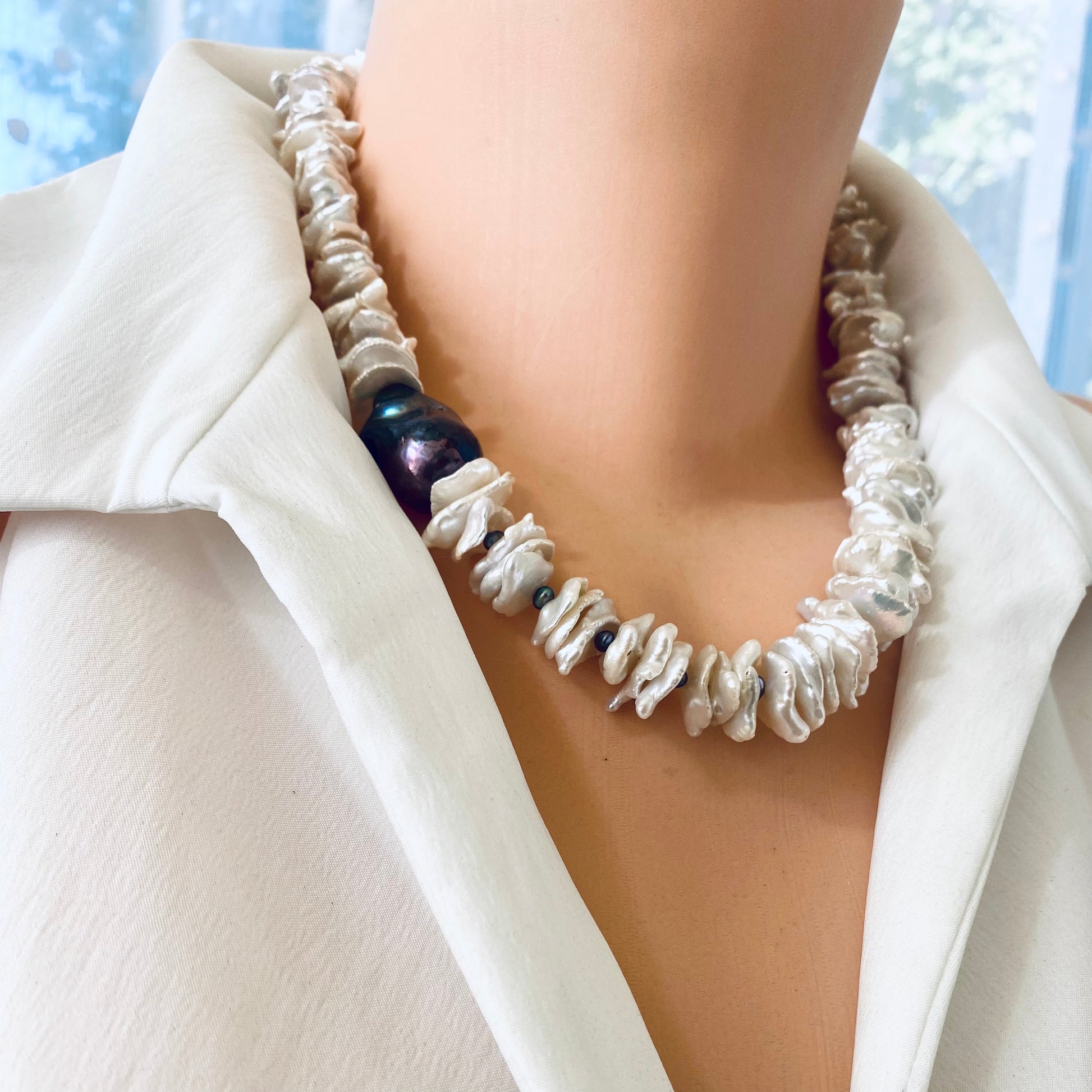 White cornflake pearl necklace with black baroque pearl pendant on a mannequin.