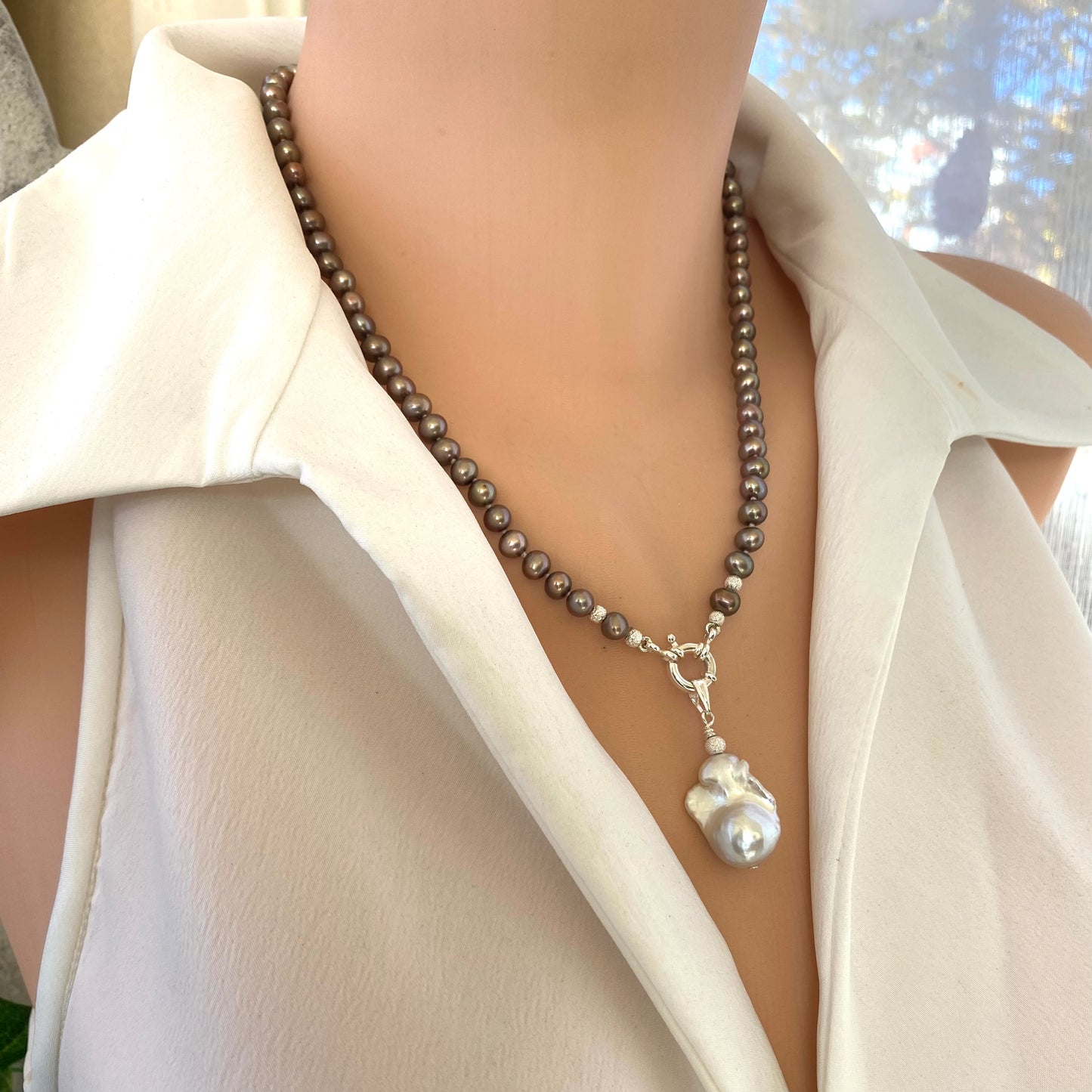 Elegant bronze pearl necklace featuring white baroque pearl pendant on mannequin, highlighting handcrafted knotted design.