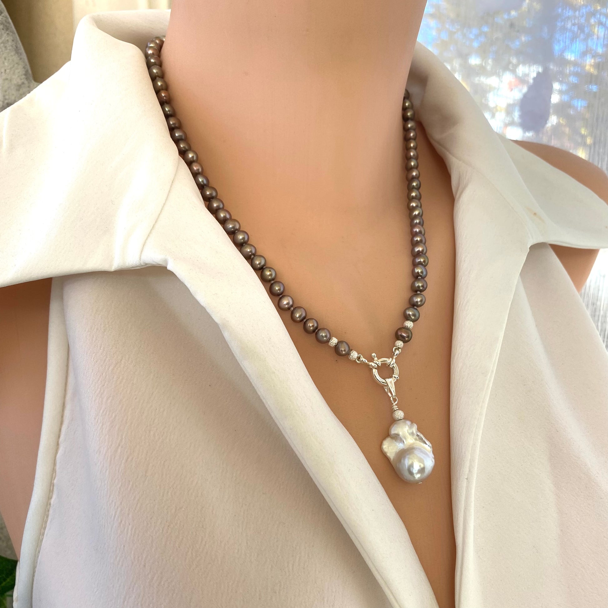 Elegant bronze pearl necklace featuring white baroque pearl pendant on mannequin, highlighting handcrafted knotted design.