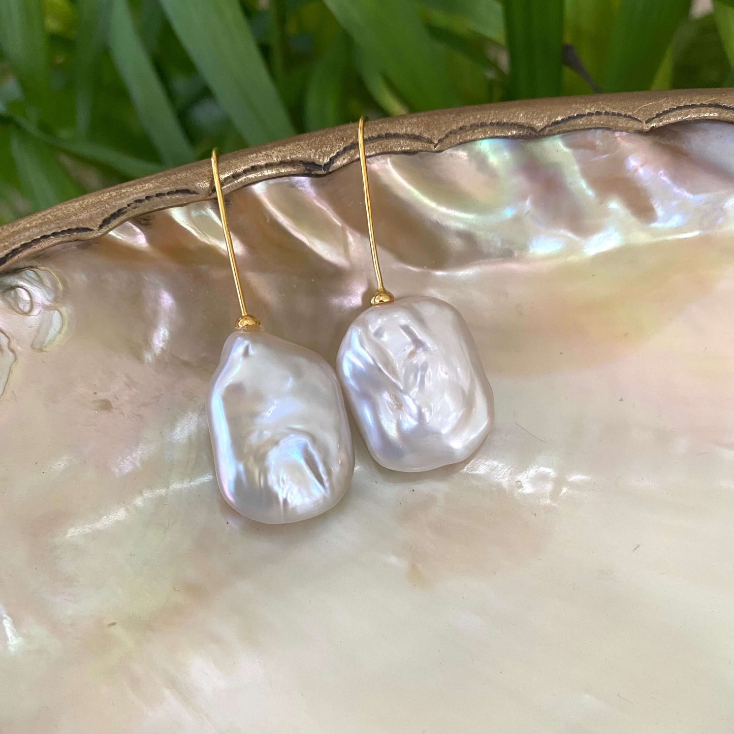 White freshwater pearl drop earrings gold vermeil close-up on pearl shell, rectangular pearls handmade in Canada.