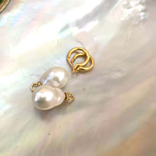 White Baroque Pearl Earrings – gold hoops and pearls displayed on white shell