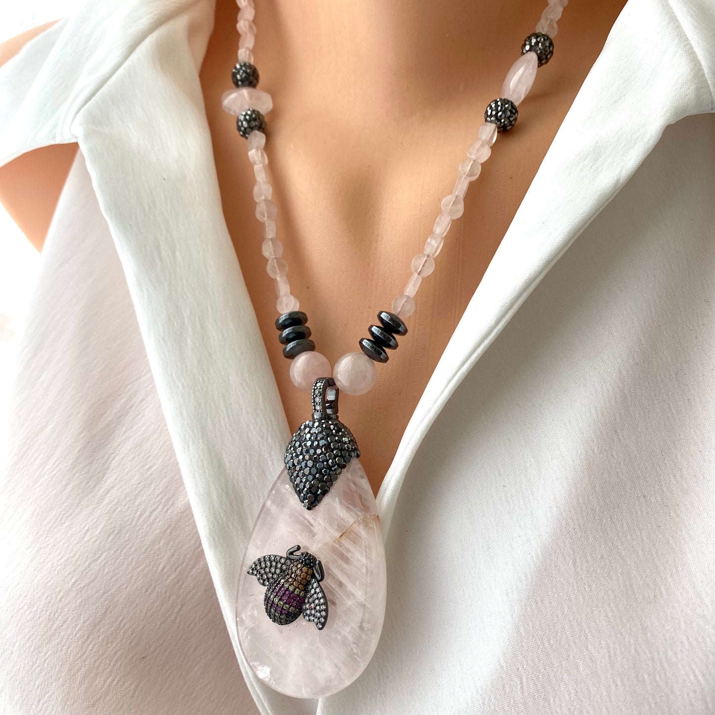 Rose quartz necklace with rhinestone pavé bee pendant showcasing blush-pink gemstones and elegant design.