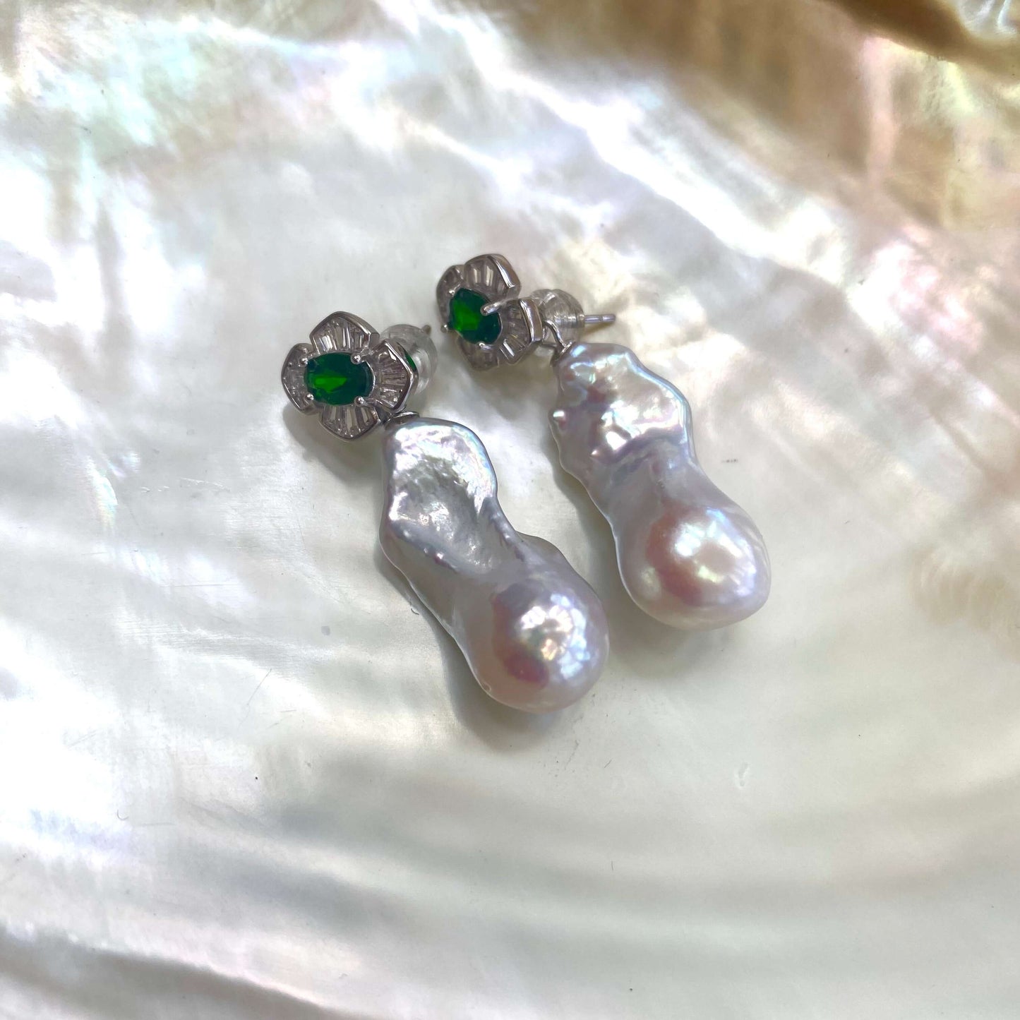 Green diopside baroque pearl drop earrings displayed on white shell backdrop — removable pearl design in rhodium-plated sterling silver