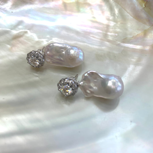 Moissanite and baroque pearl earrings close-up on white pearl shell, handcrafted in Canada.