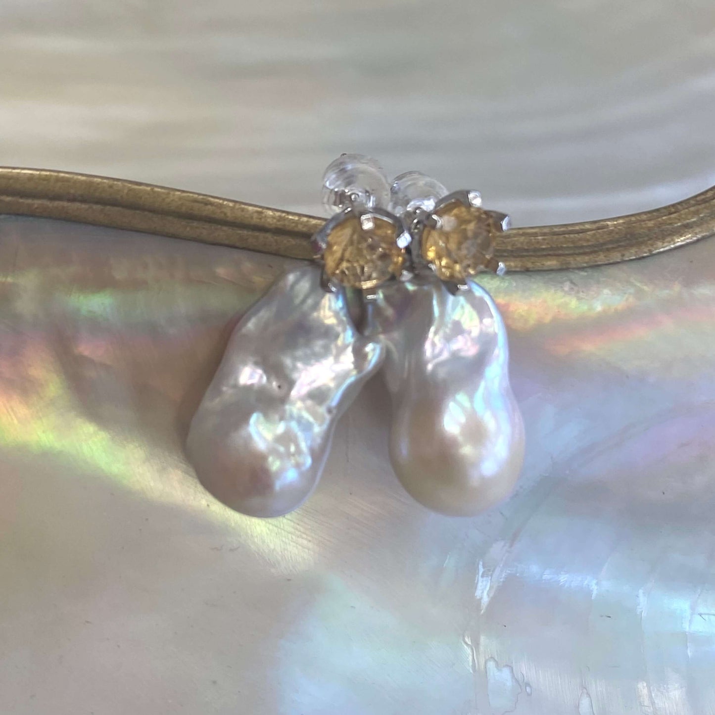 Citrine stud earrings with baroque pearls on white pearl shell background