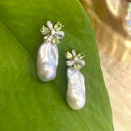 Peridot stud earrings with baroque pearl drops on green leaf backdrop