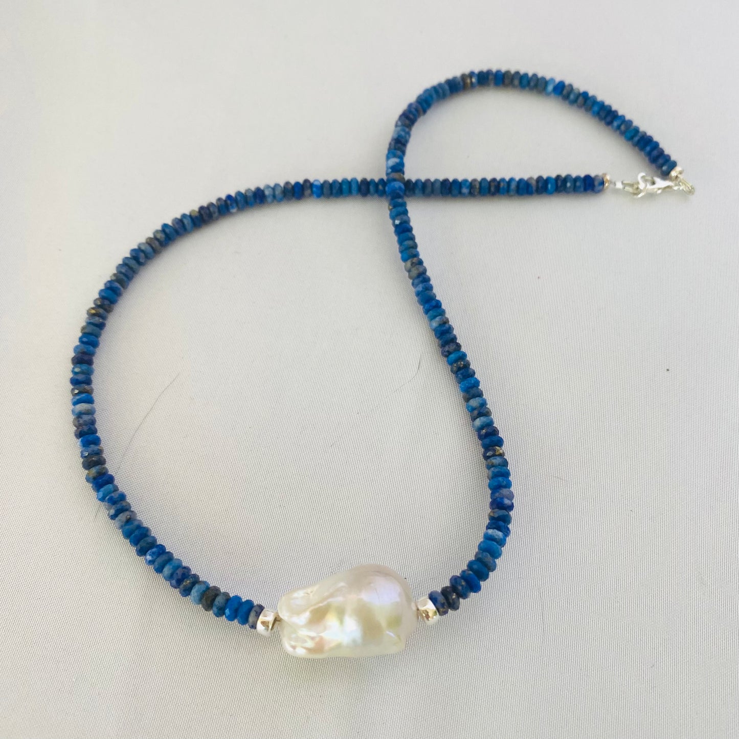 Lapis lazuli baroque pearl necklace featuring deep blue gemstones and a unique freshwater pearl centerpiece.