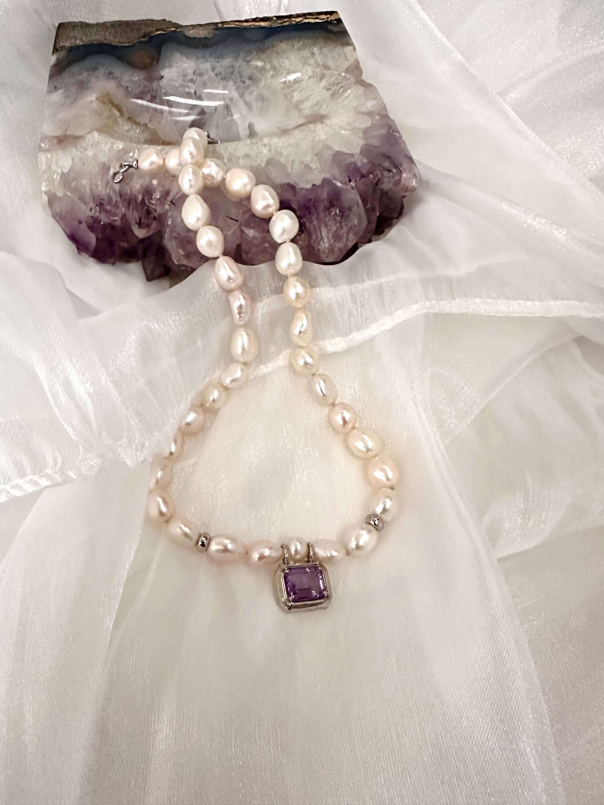 White Nugget Pearl Necklace with Amethyst Pendant – 'Viola' Collection on a soft fabric background.