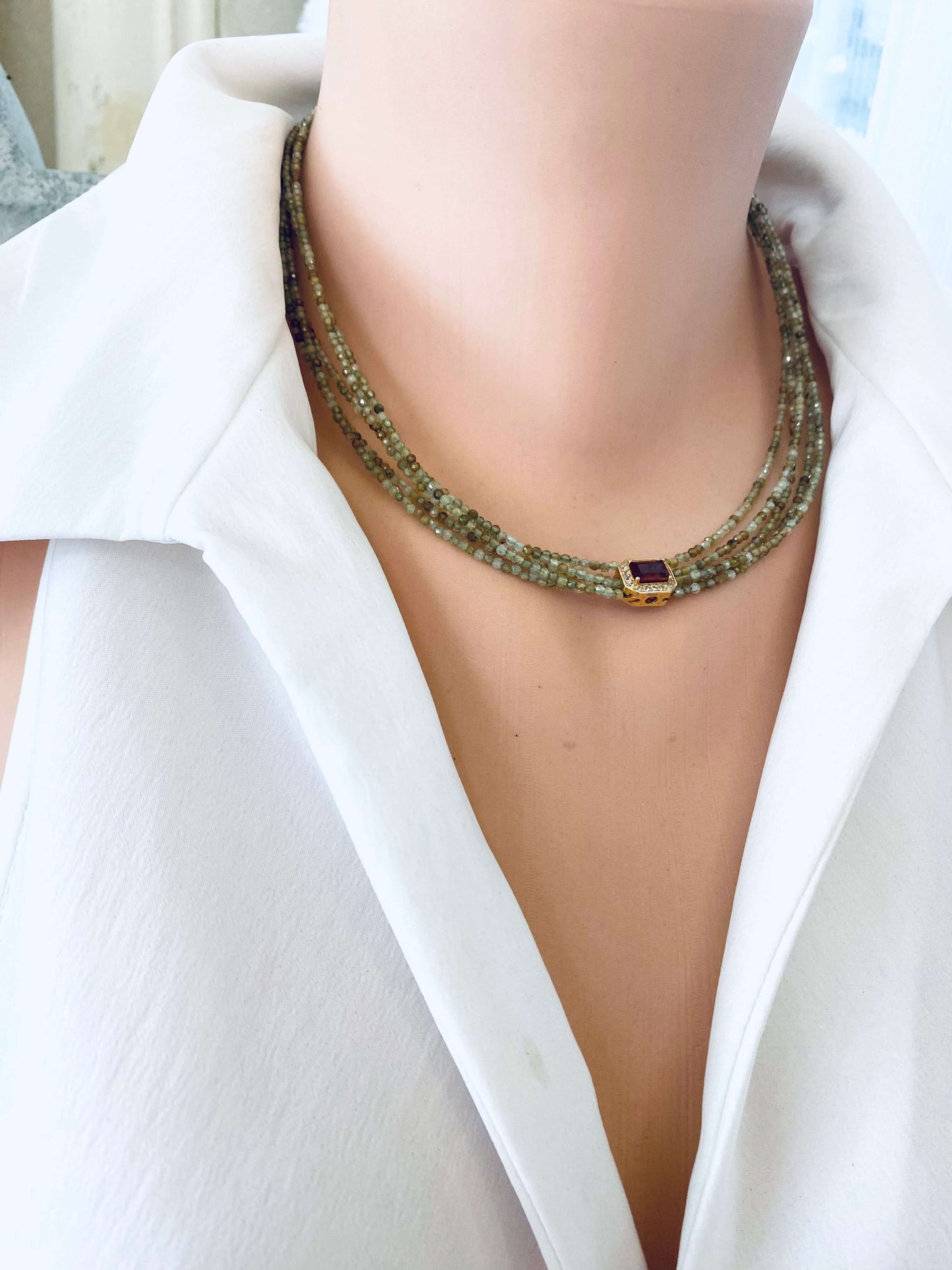 Green orange garnet necklace displayed on a mannequin, featuring multi-strand gold vermeil and 2 mm faceted garnet beads.