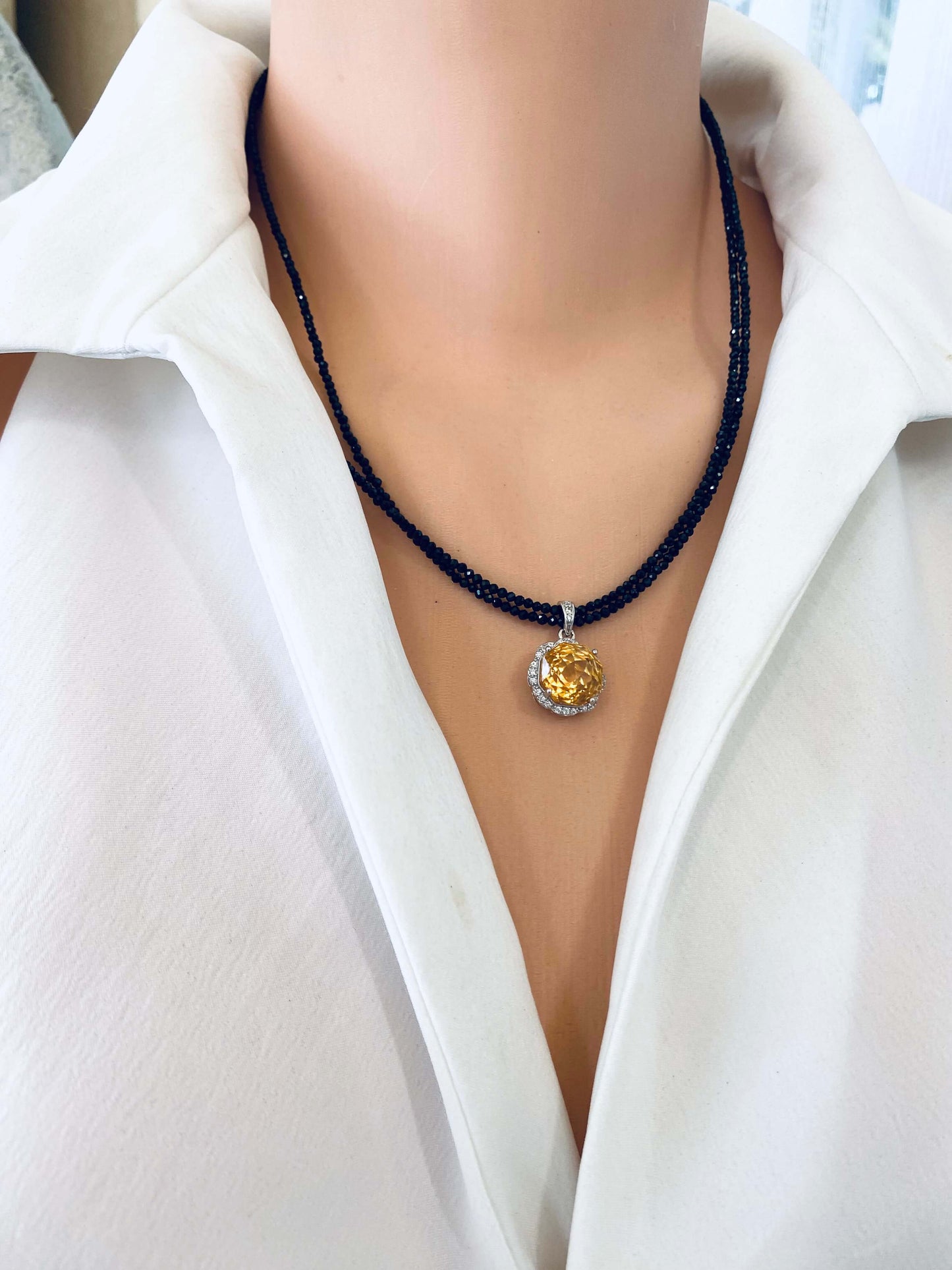 Close-up side angle of black spinel and citrine pendant necklace with silver clasp