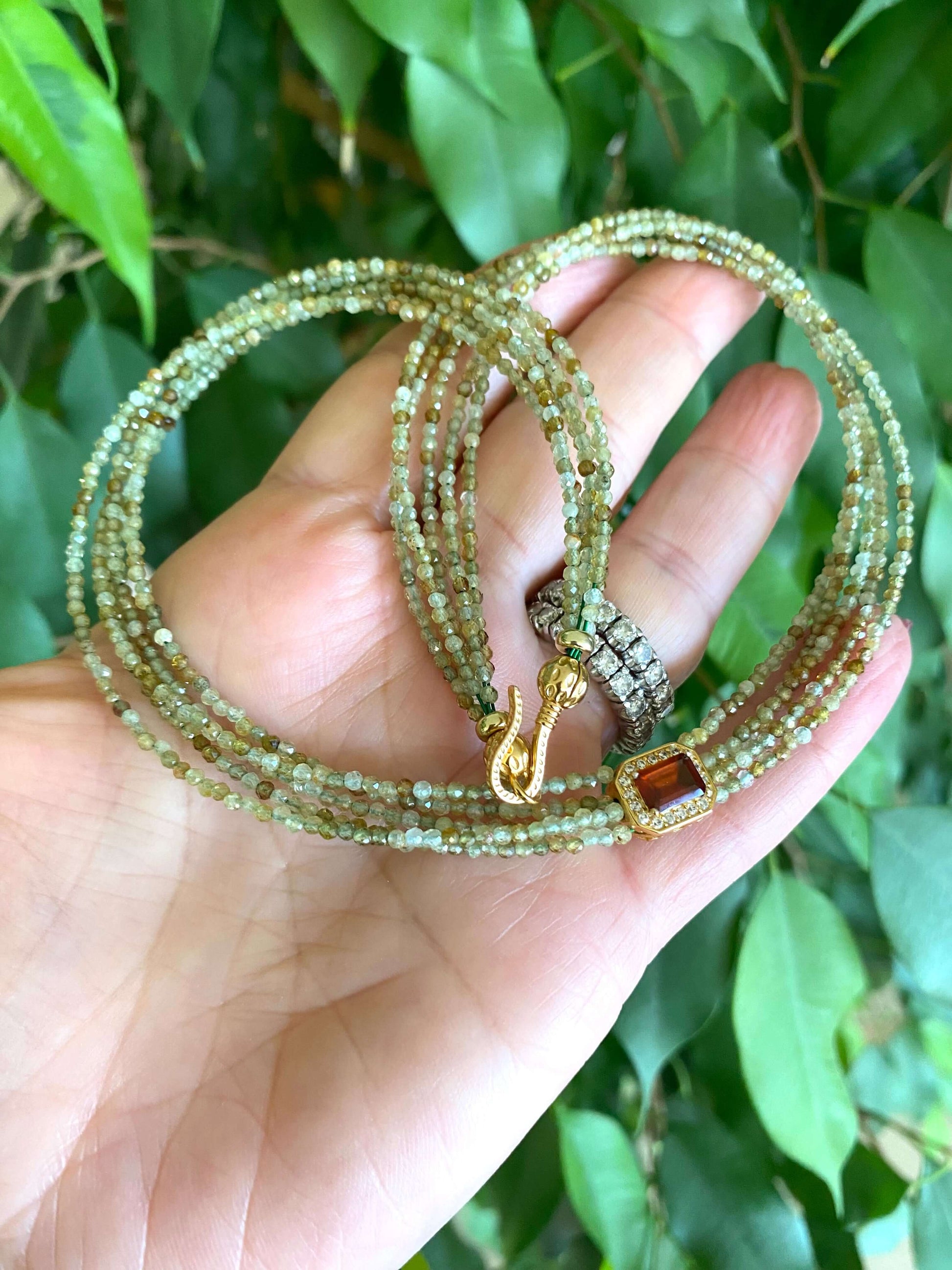 Green orange garnet necklace showcasing multi-strand gold vermeil with green garnet beads and orange garnet centerpiece.