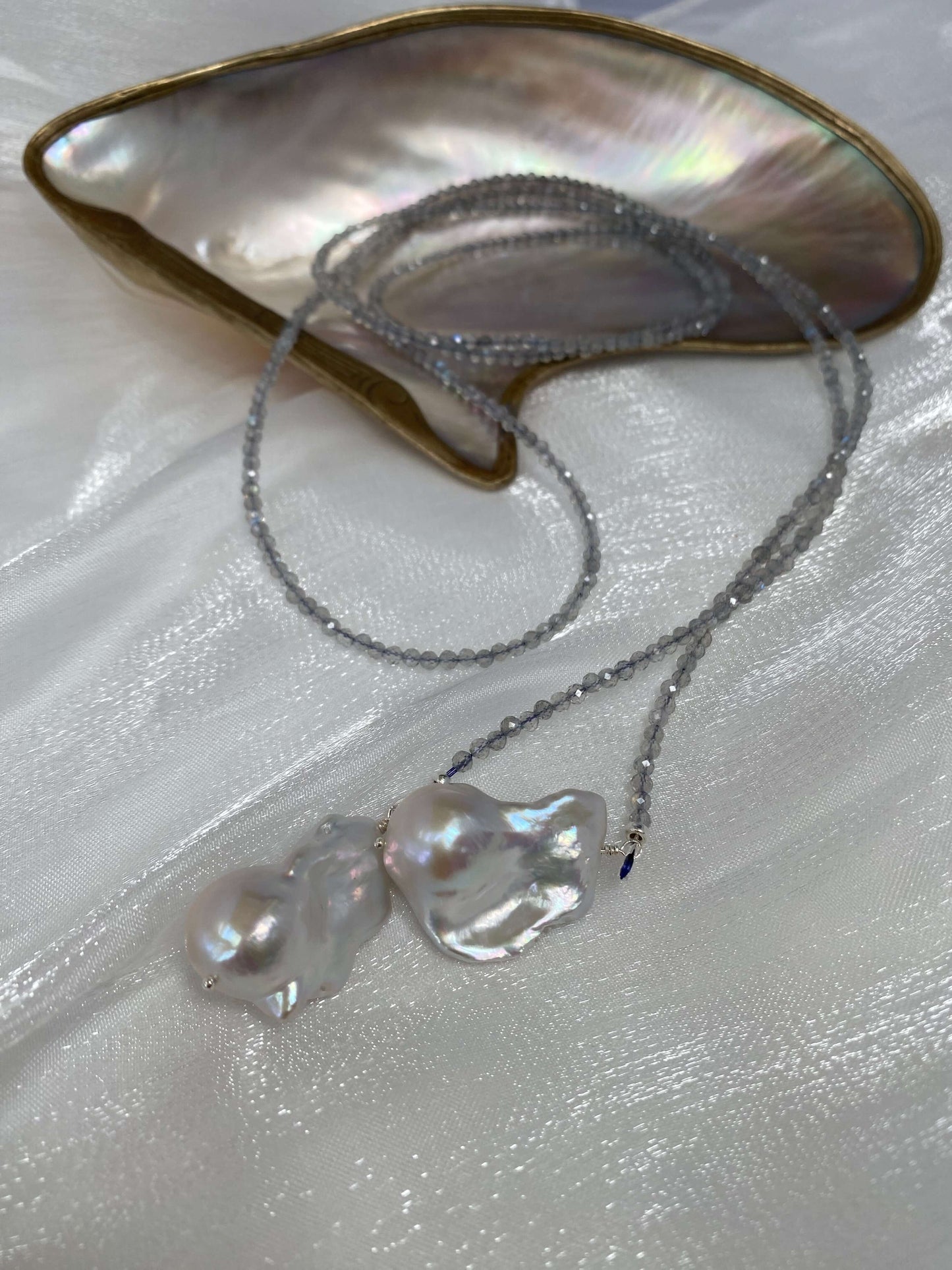 Labradorite and Baroque Pearl Necklace displayed on a silky surface with an abalone shell.