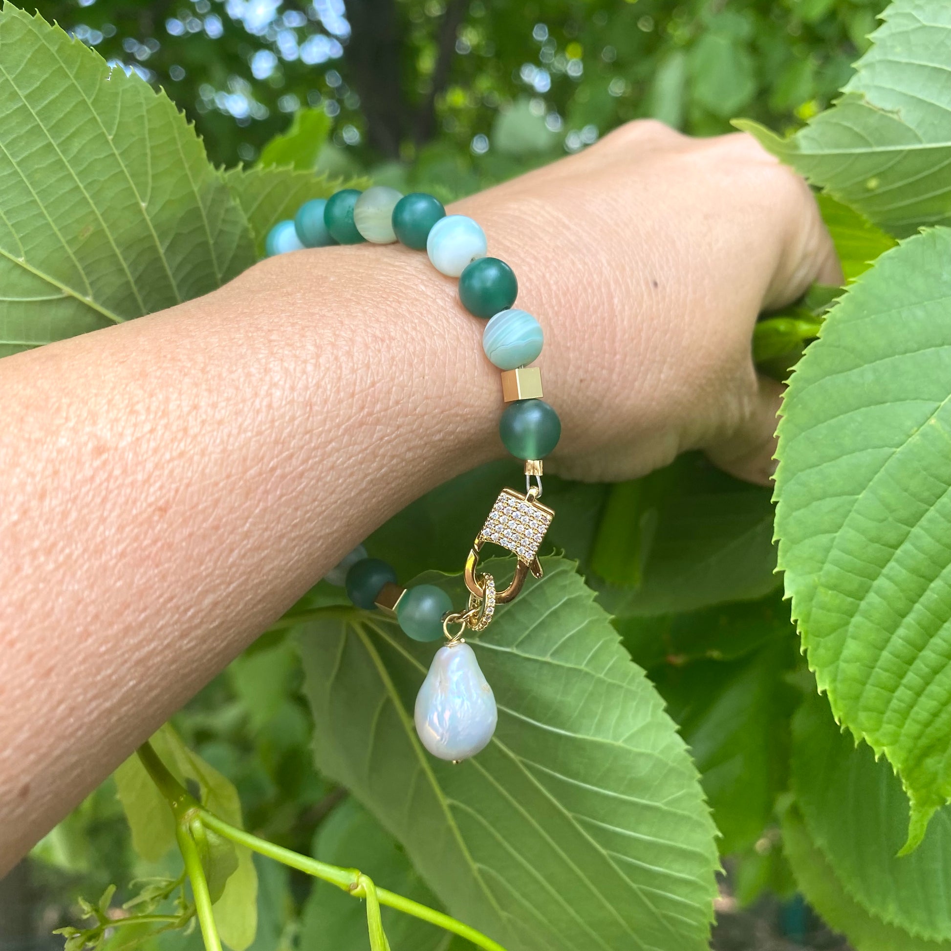 Sardonyx baroque pearl bracelet worn on wrist showing green beads and pearl charm