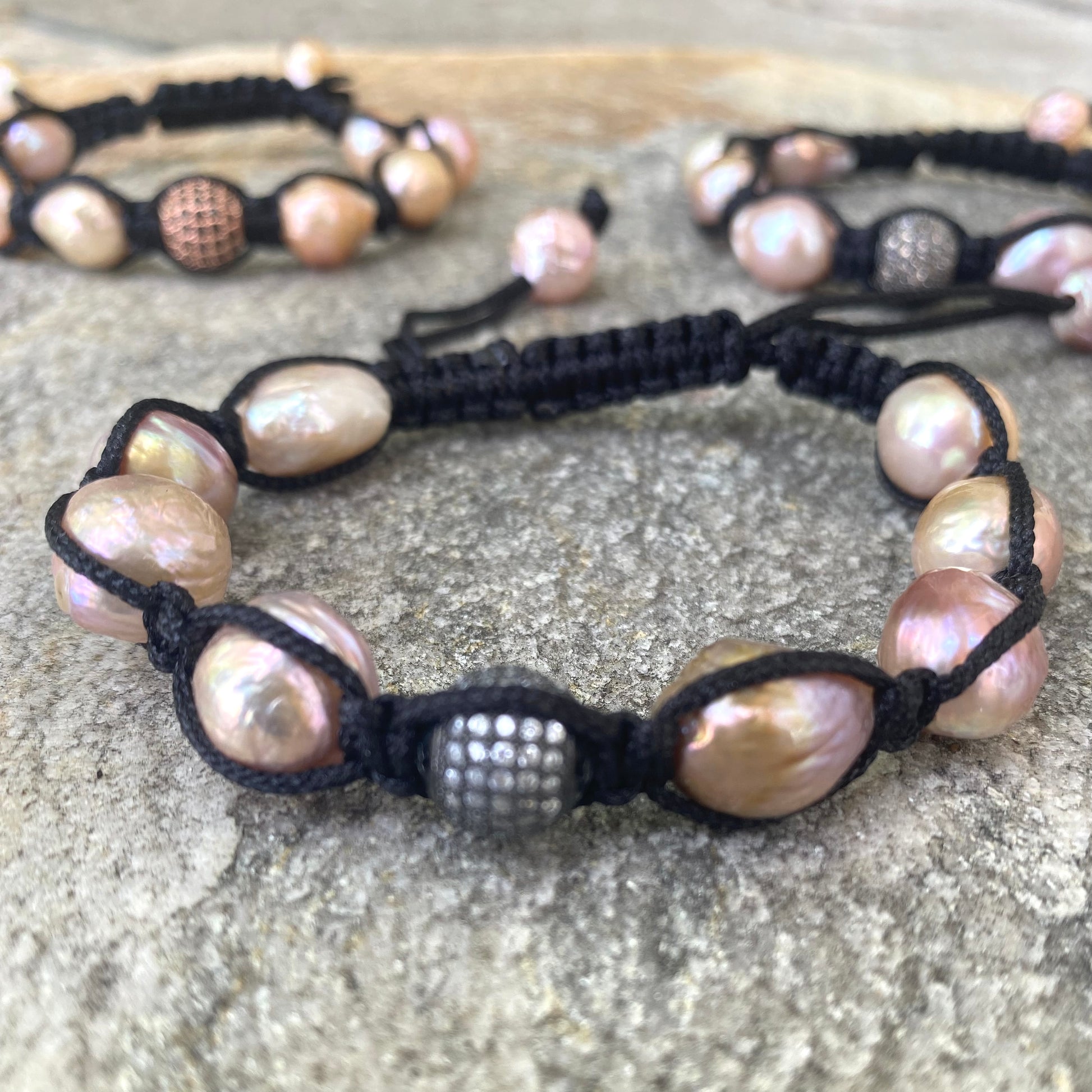 Baroque pearl bracelet featuring pastel baroque pearls on black macramé thread, showcasing organic texture and refined sparkle.