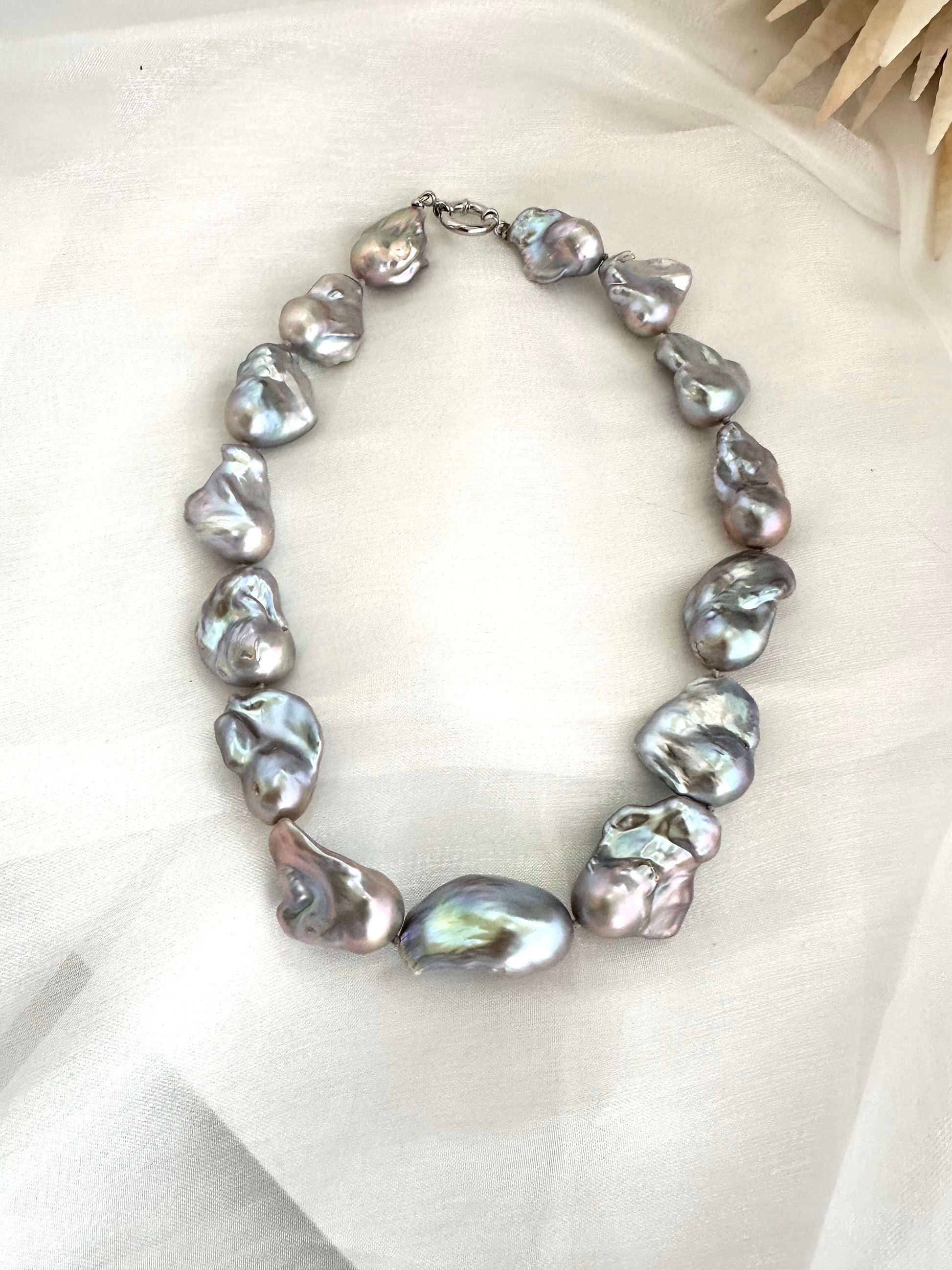 Baroque pearl necklace with silver details, showcasing large, iridescent baroque pearls in an organic design.