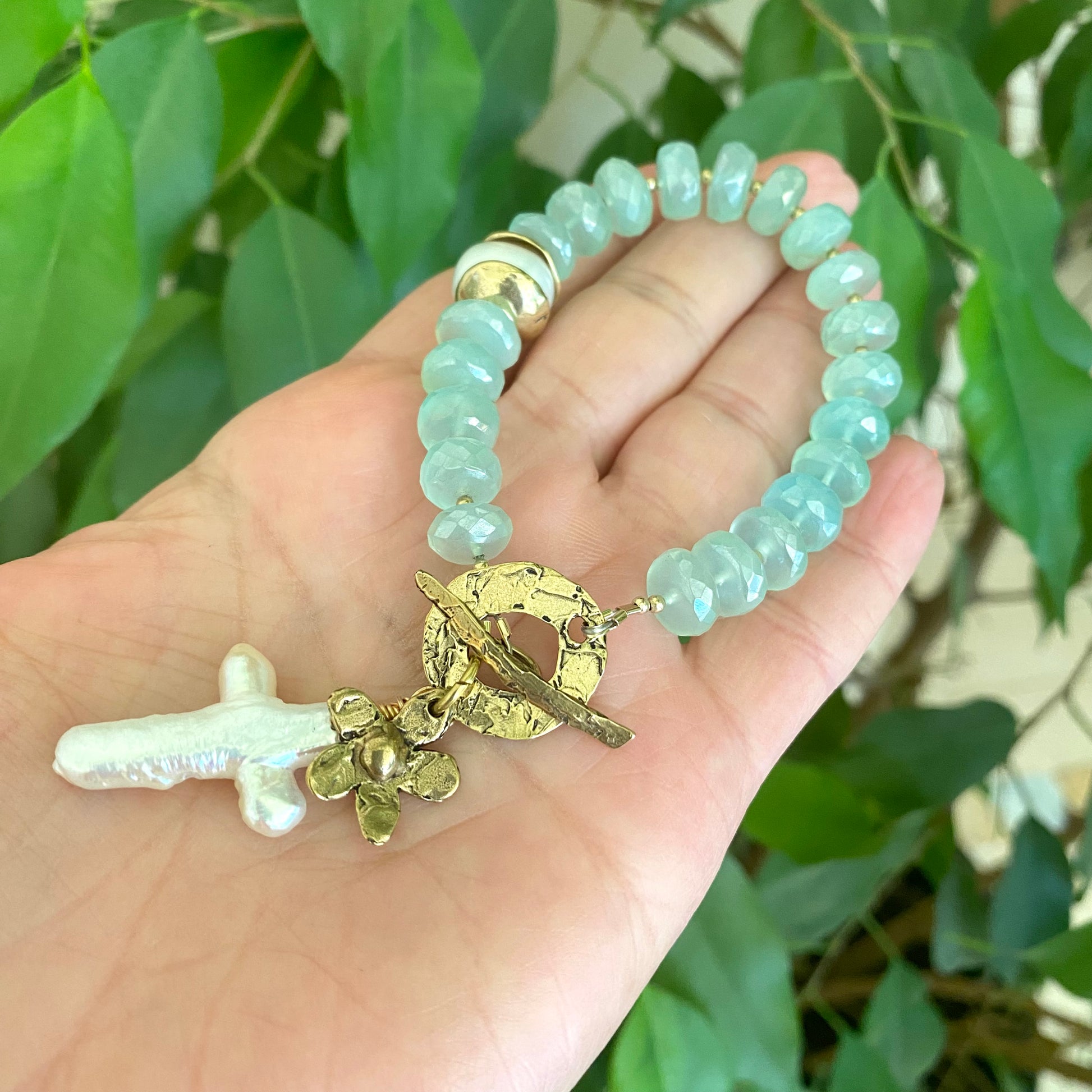 Chalcedony bracelet with cross pearl pendant and daisy charm, featuring aqua green chalcedony beads.