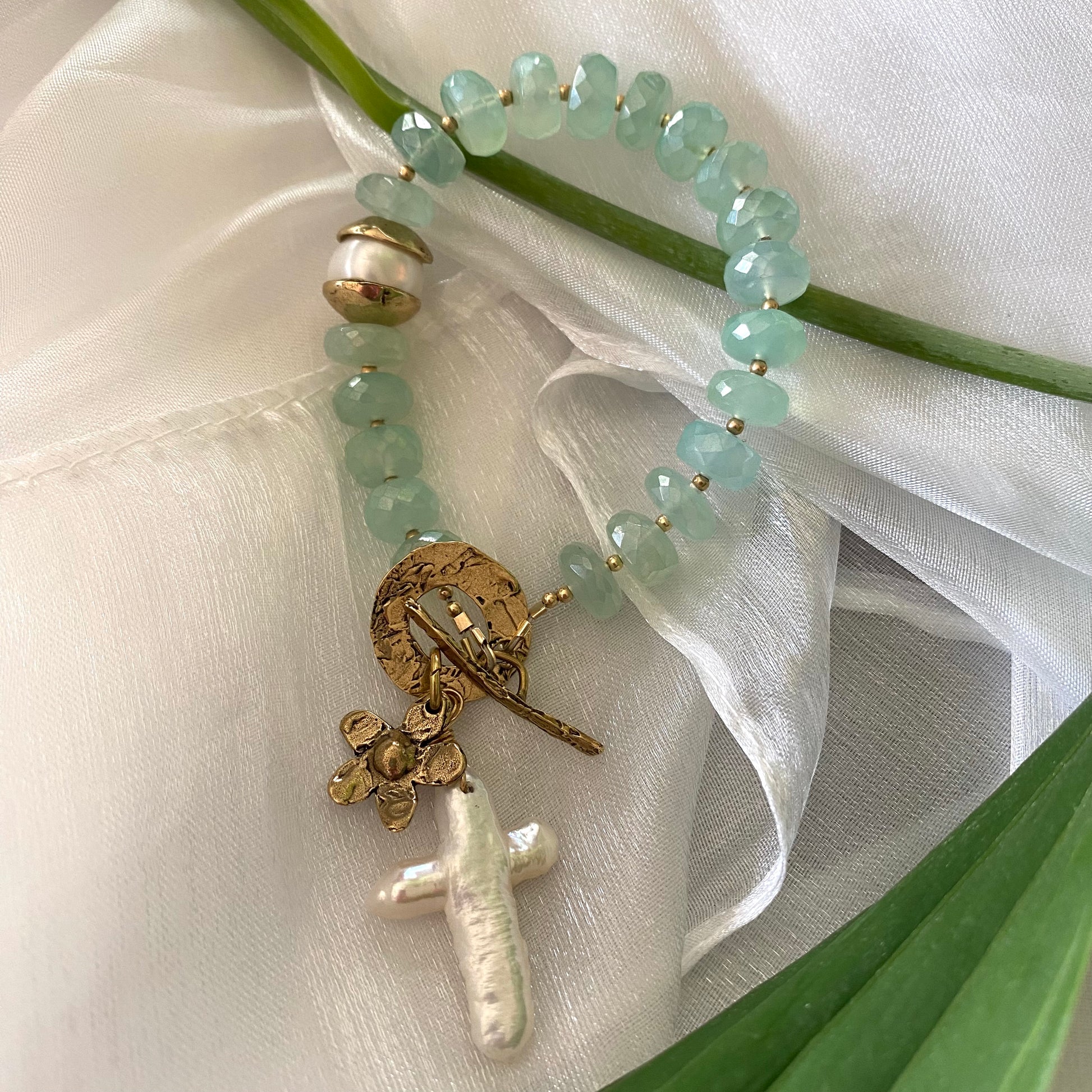 Chalcedony bracelet with cross pearl pendant and daisy charm, featuring aqua green chalcedony rondelle beads.