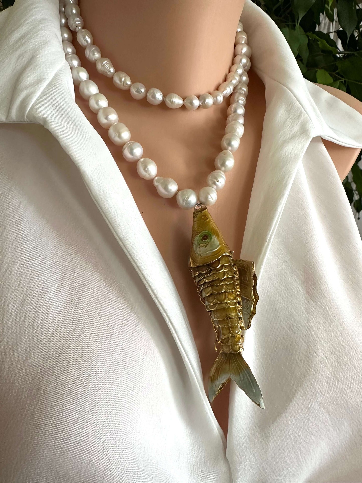 Baroque pearl necklace with fish pendant showcased on a mannequin wearing a white shirt.