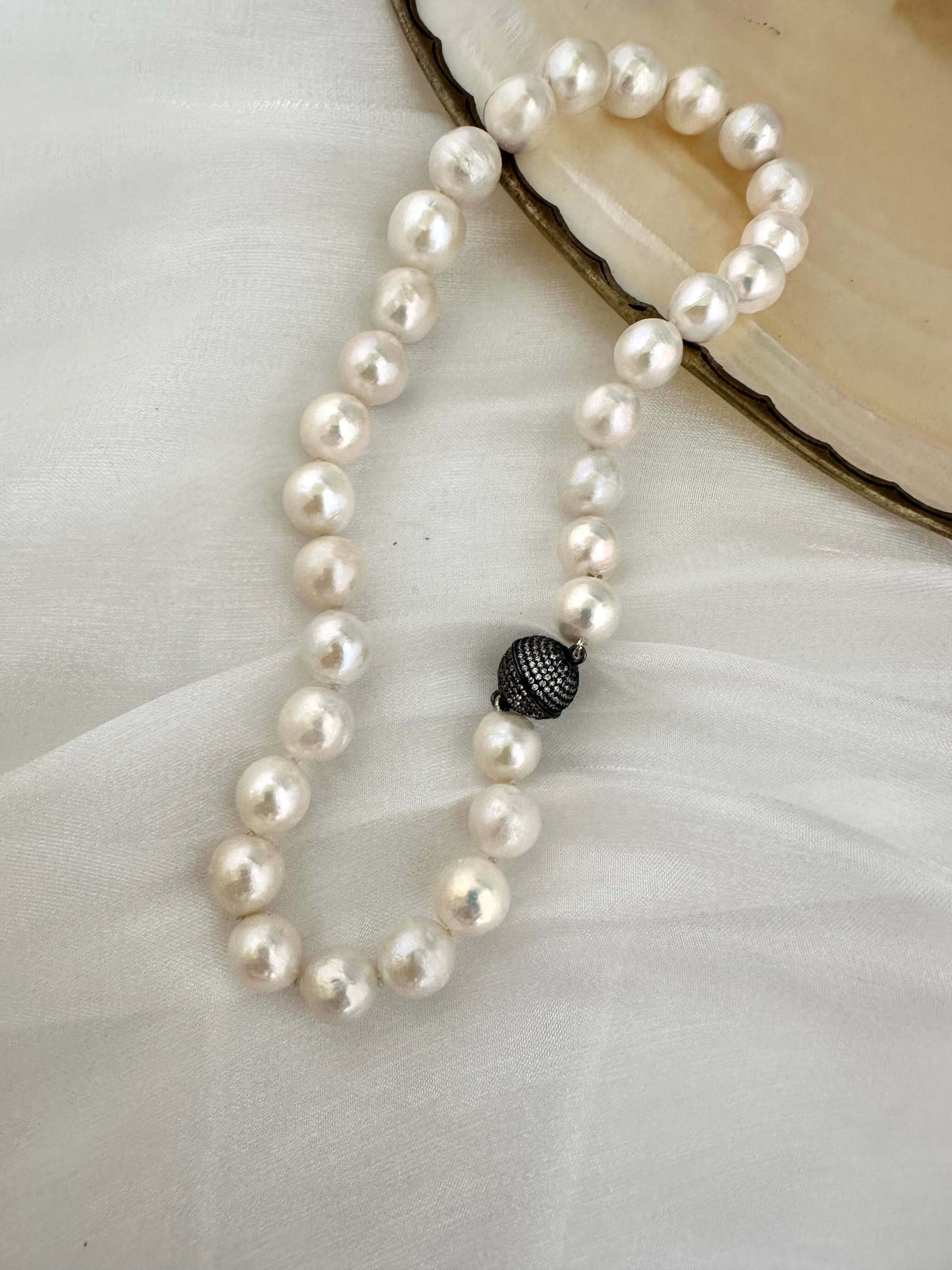 White Edison pearl necklace with gunmetal pavé magnetic clasp on soft fabric background.