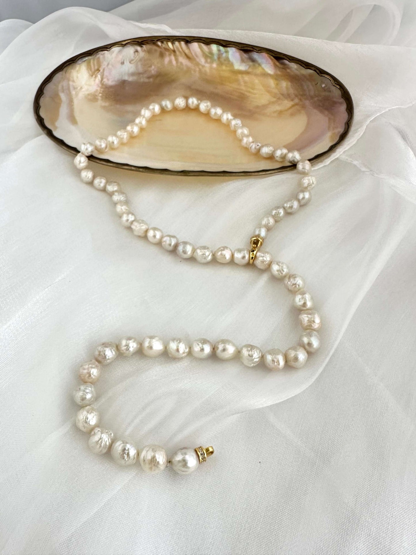 Edison pearl Y necklace featuring organic baroque pearls displayed on an elegant shell plate.