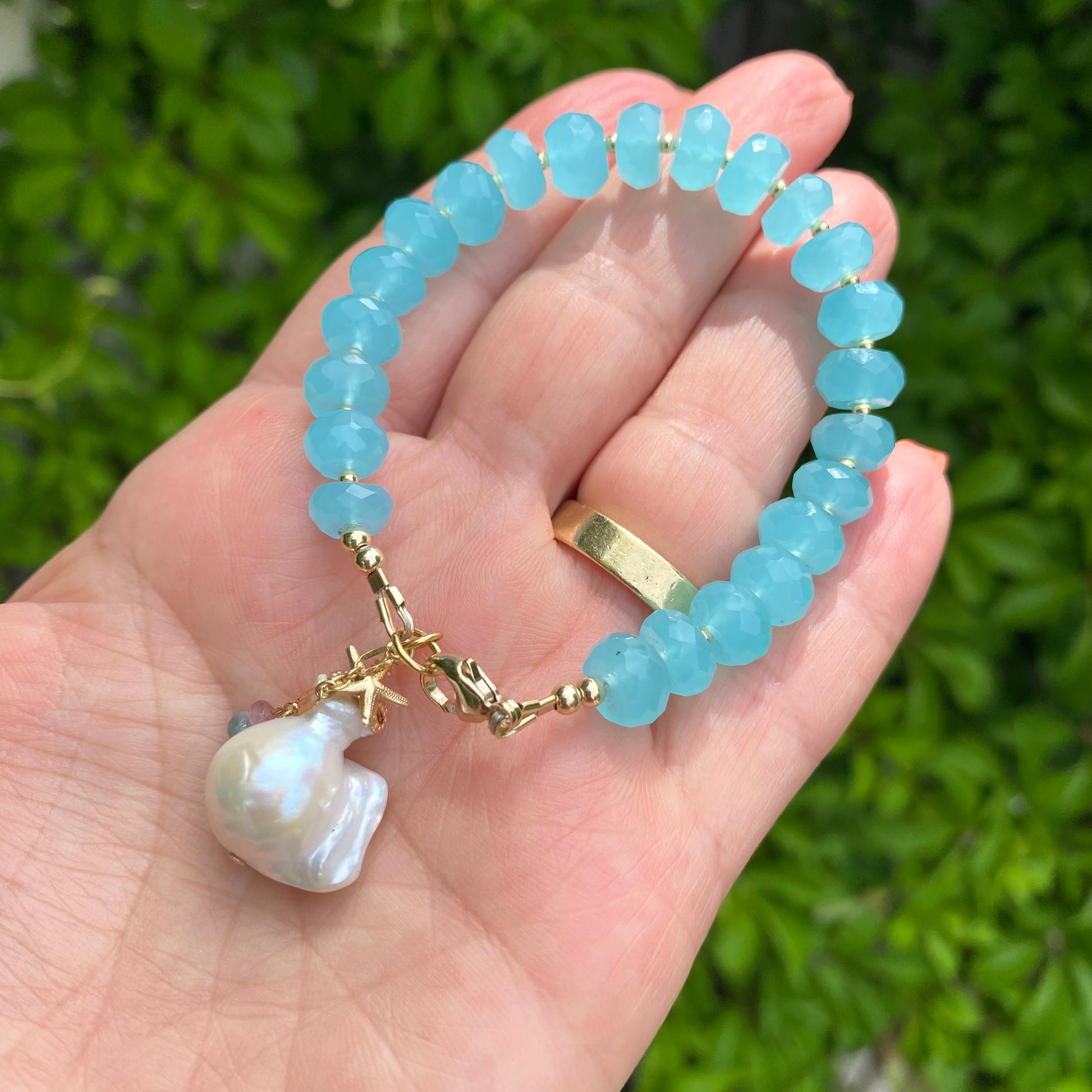 Chalcedony bracelet featuring aqua blue beads, starfish charm, and baroque pearl, showcasing ocean-inspired elegance.